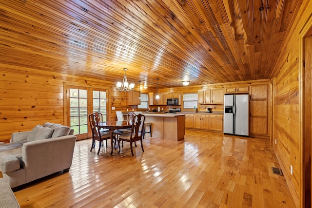 kitchen featuring wooden walls, decorative light fixtures, light hardwood / wood-style floors, and appliances with stainless steel finishes