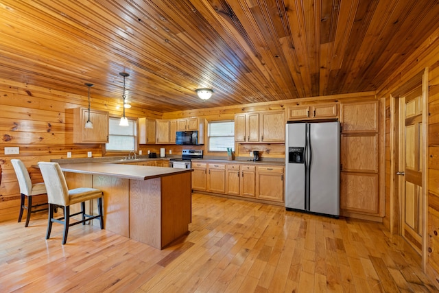 kitchen with stainless steel appliances, wooden walls, decorative light fixtures, light hardwood / wood-style floors, and a kitchen island