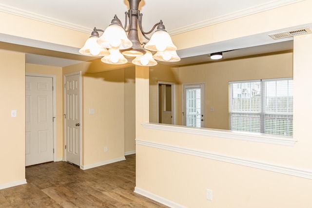 spare room featuring a chandelier, hardwood / wood-style flooring, and crown molding