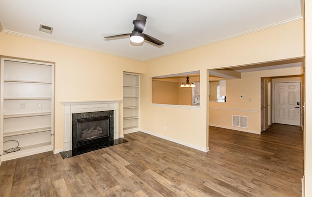 unfurnished living room with hardwood / wood-style floors, built in shelves, crown molding, and a high end fireplace