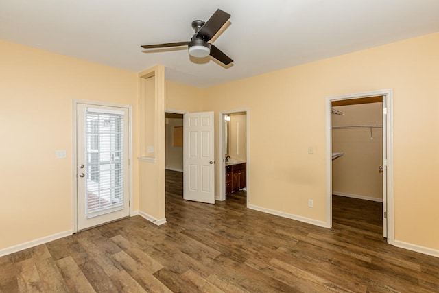 unfurnished bedroom with dark hardwood / wood-style flooring, a closet, a spacious closet, and ceiling fan