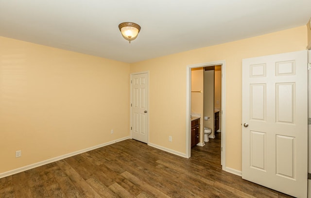 unfurnished bedroom with ensuite bath and dark wood-type flooring