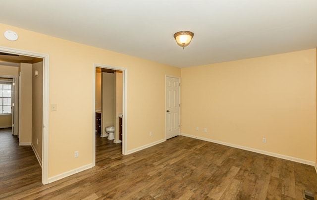 interior space featuring ensuite bath and dark wood-type flooring