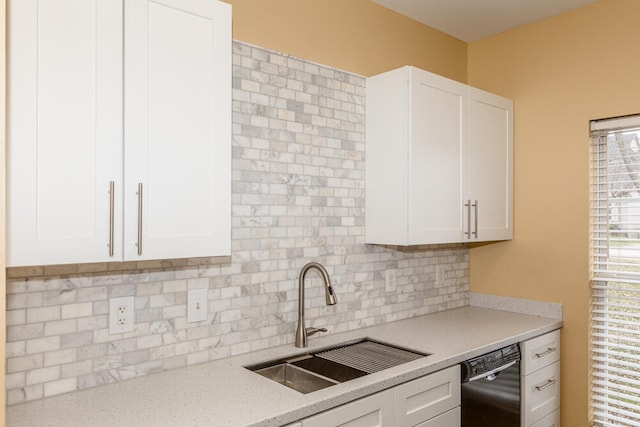 kitchen with white cabinetry, sink, light stone countertops, black dishwasher, and tasteful backsplash