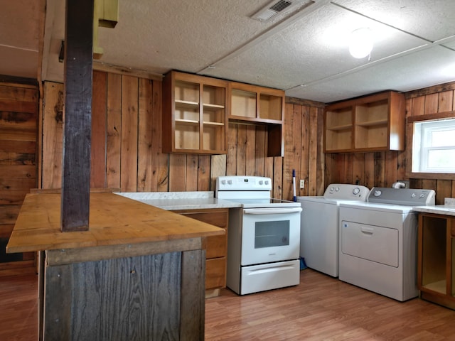 kitchen with washing machine and dryer, wooden walls, light hardwood / wood-style flooring, and white electric stove