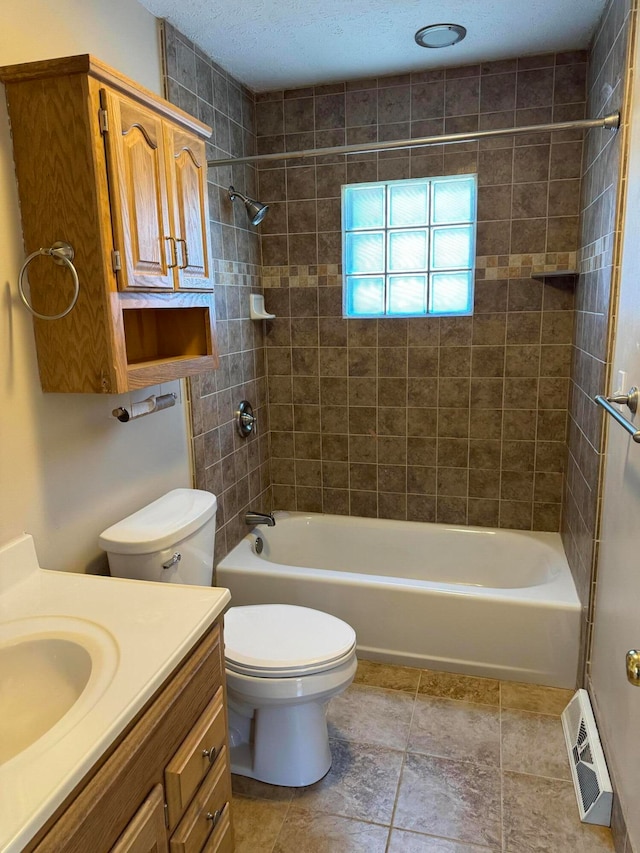 full bathroom with a textured ceiling, vanity, toilet, and tiled shower / bath