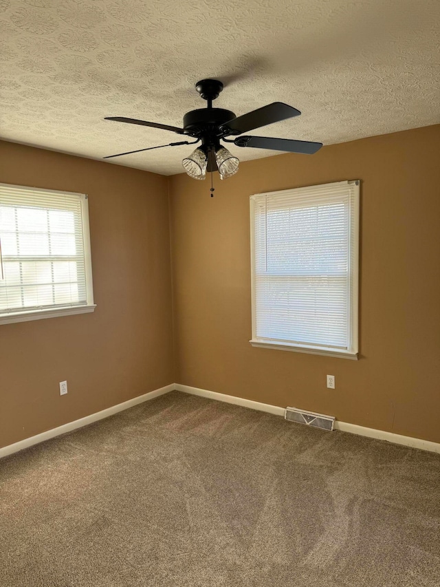 carpeted spare room with a textured ceiling and ceiling fan