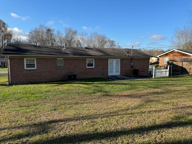 back of property with a yard, central air condition unit, and french doors