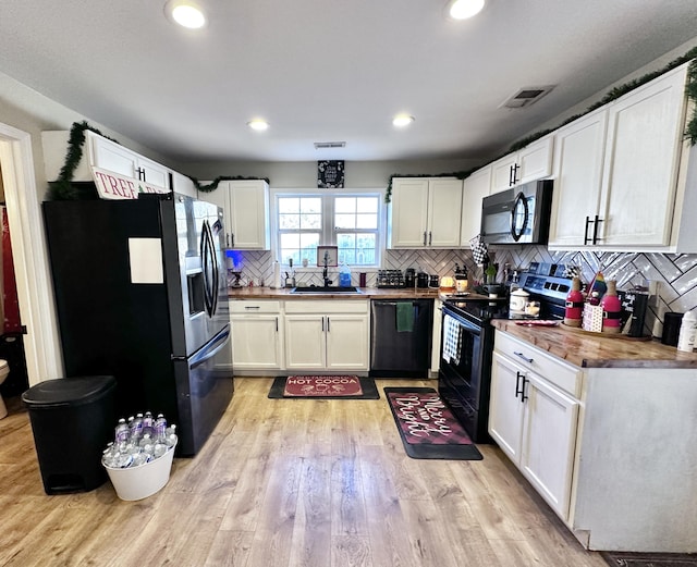 kitchen featuring black appliances, white cabinets, sink, light wood-type flooring, and butcher block countertops