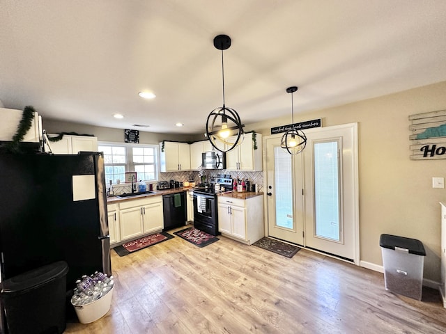 kitchen featuring tasteful backsplash, sink, black appliances, decorative light fixtures, and light hardwood / wood-style flooring