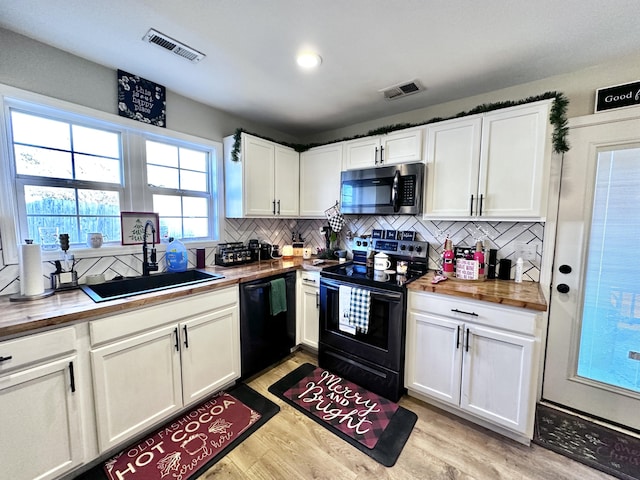 kitchen featuring sink, white cabinetry, butcher block counters, and black appliances