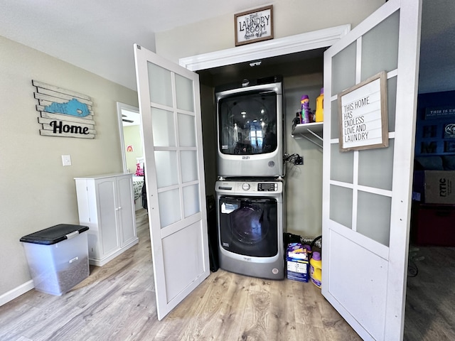 clothes washing area featuring light hardwood / wood-style floors and stacked washer / drying machine