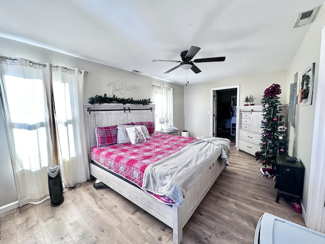 bedroom featuring ceiling fan, light wood-type flooring, and multiple windows