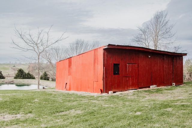 view of outdoor structure featuring a water view and a yard