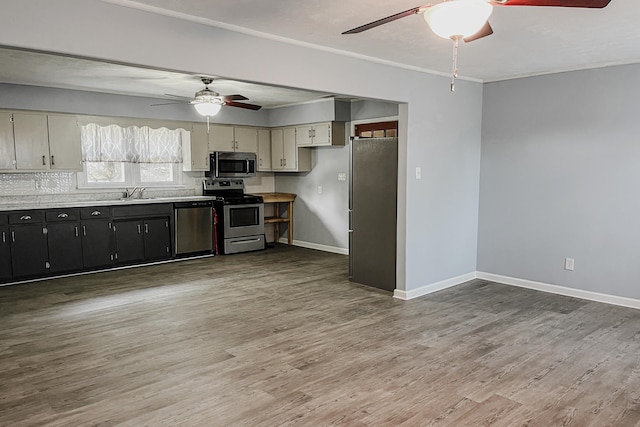 kitchen featuring sink, stainless steel appliances, tasteful backsplash, cream cabinets, and hardwood / wood-style flooring