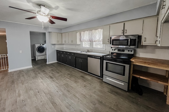 kitchen featuring ceiling fan, sink, stainless steel appliances, washer / dryer, and hardwood / wood-style flooring