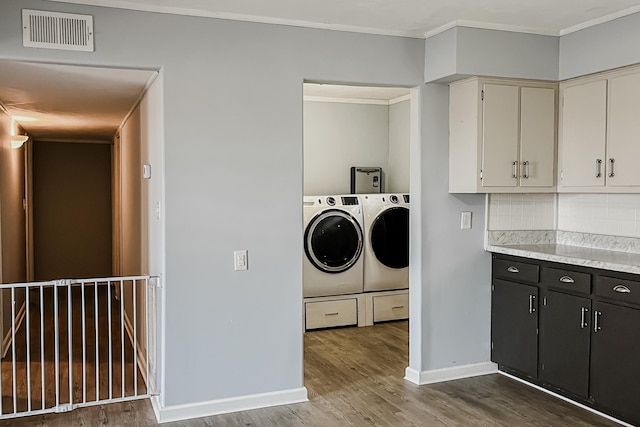 laundry area featuring ornamental molding, washer and dryer, and wood-type flooring