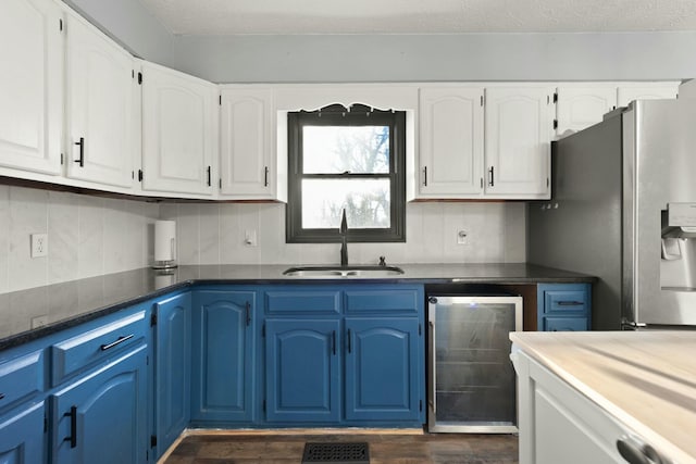 kitchen featuring stainless steel fridge with ice dispenser, sink, white cabinets, and beverage cooler