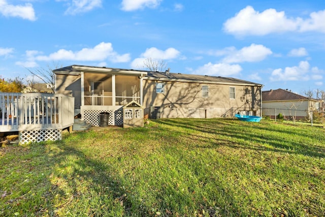 rear view of property with a sunroom, a yard, and a wooden deck