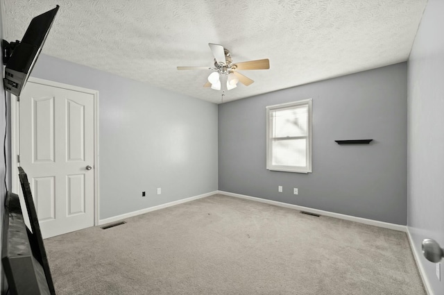 carpeted empty room featuring ceiling fan and a textured ceiling