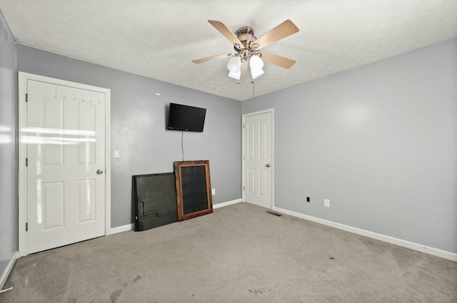 unfurnished bedroom featuring a textured ceiling, light colored carpet, and ceiling fan