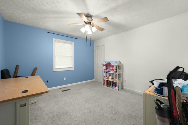 carpeted office space featuring a textured ceiling and ceiling fan