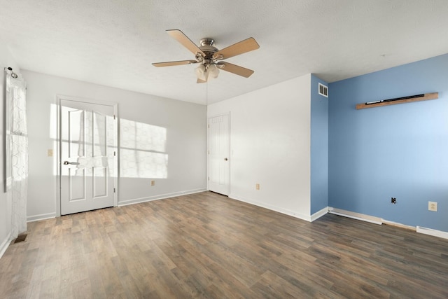 empty room featuring ceiling fan, dark wood-type flooring, and a textured ceiling