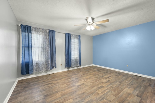 unfurnished room with ceiling fan, dark wood-type flooring, and a textured ceiling