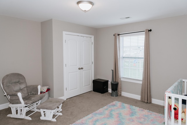 carpeted bedroom featuring a closet and a nursery area