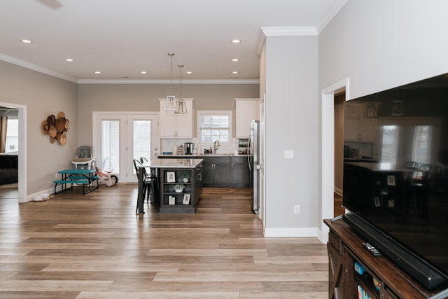 dining area featuring french doors, light hardwood / wood-style floors, ornamental molding, and sink