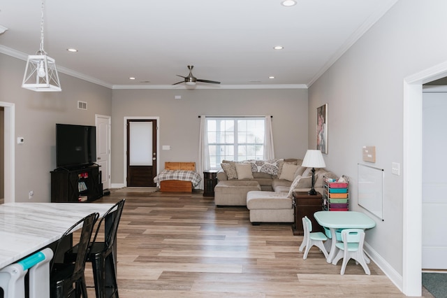 living room with ceiling fan, ornamental molding, and light wood-type flooring