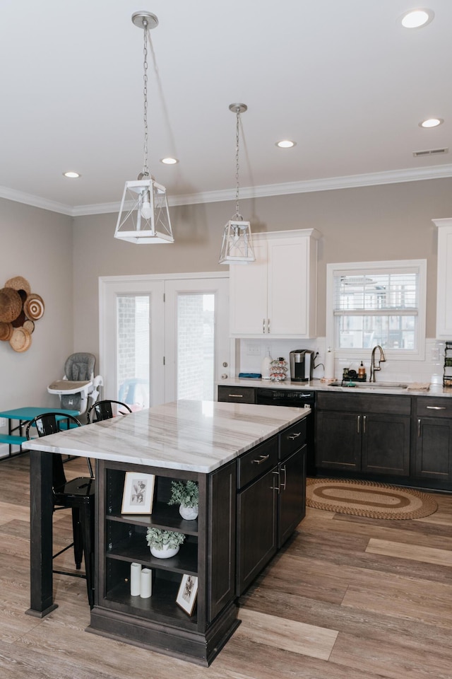 kitchen featuring light stone countertops, white cabinetry, a center island, sink, and light hardwood / wood-style flooring