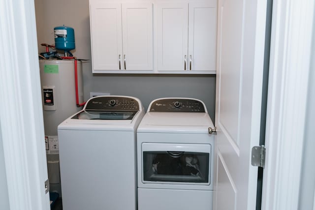 clothes washing area with cabinets, electric water heater, and separate washer and dryer