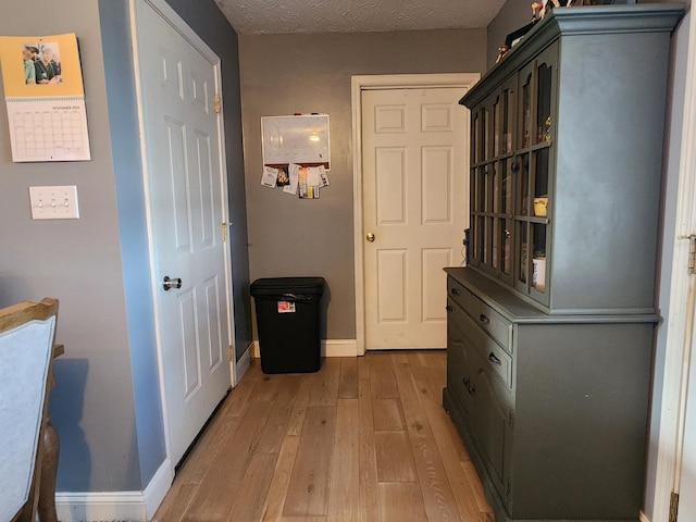 hallway featuring a textured ceiling and light hardwood / wood-style floors