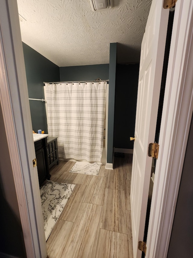 bathroom with vanity, wood-type flooring, a textured ceiling, and a shower with shower curtain