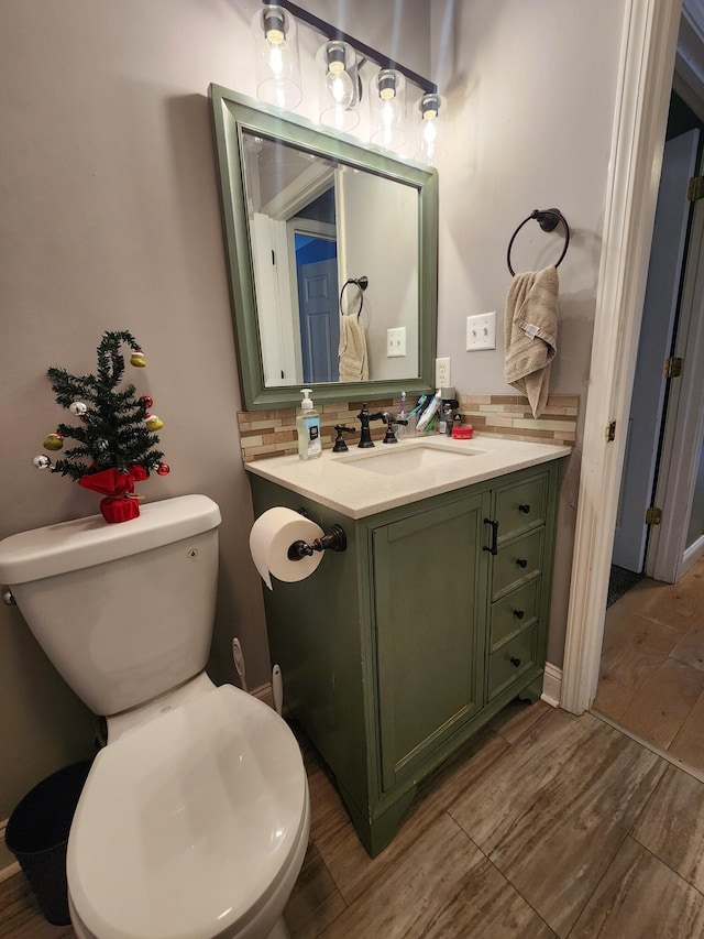 bathroom with decorative backsplash, toilet, wood-type flooring, and vanity