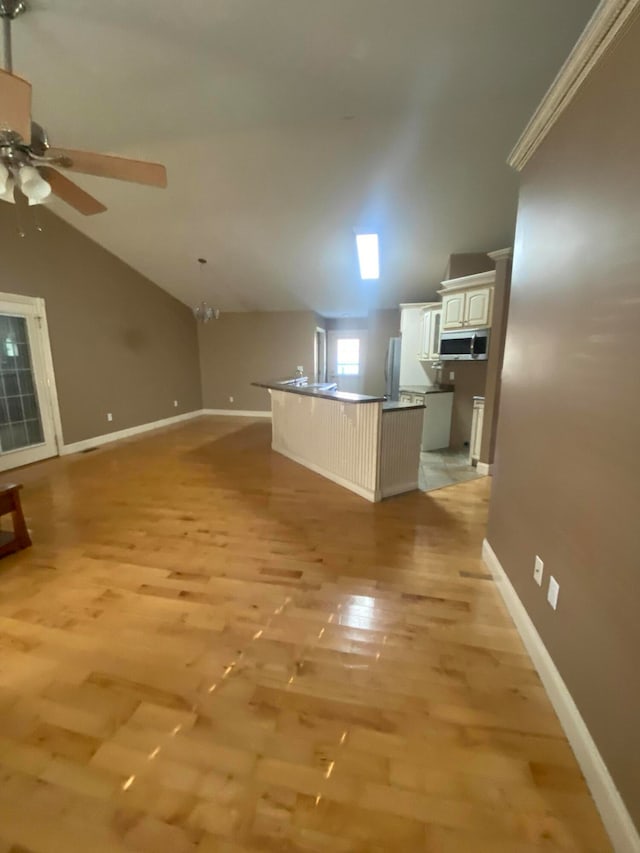 kitchen with stainless steel appliances, an island with sink, light hardwood / wood-style floors, lofted ceiling, and white cabinets