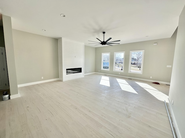 unfurnished living room with a fireplace, baseboards, light wood finished floors, and ceiling fan