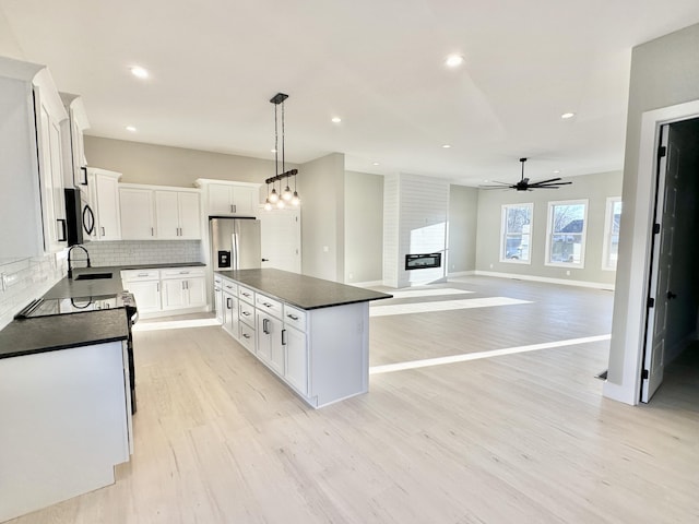 kitchen featuring dark countertops, light wood-type flooring, backsplash, and a center island