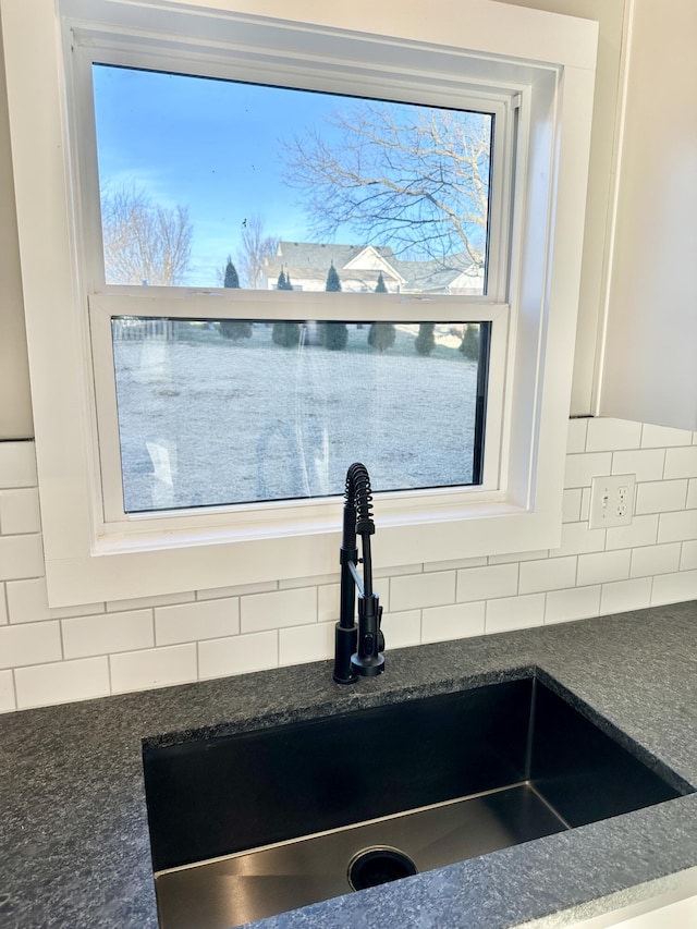 interior details featuring a sink, dark stone counters, and tasteful backsplash