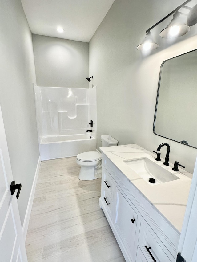 full bath featuring vanity, wood finished floors, baseboards, shower / bath combination, and toilet