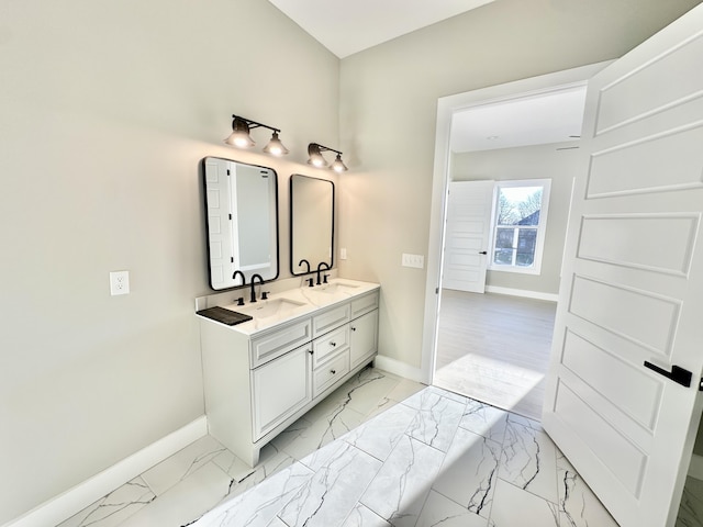 bathroom featuring double vanity, baseboards, marble finish floor, and a sink