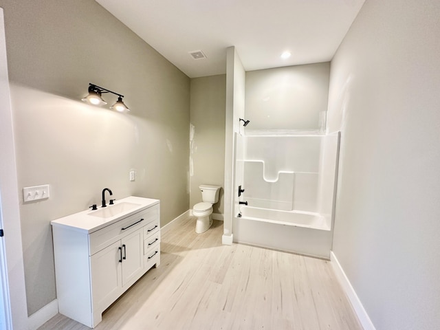 bathroom featuring visible vents, baseboards, toilet, wood finished floors, and vanity