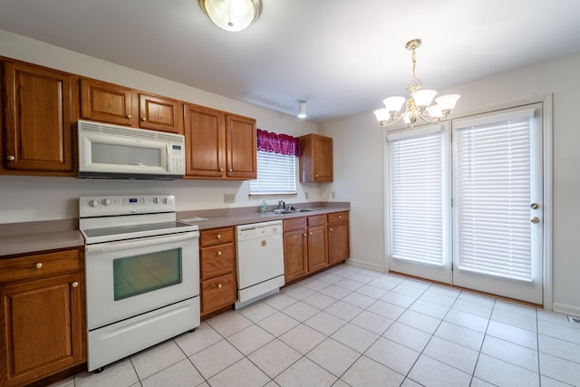 kitchen with white appliances, sink, light tile patterned floors, a chandelier, and hanging light fixtures