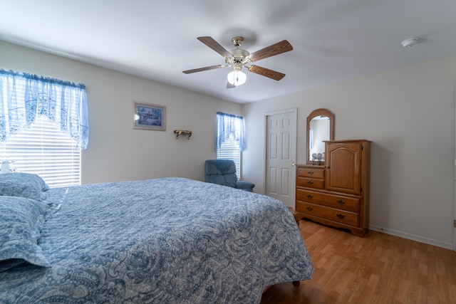 bedroom featuring ceiling fan, light wood-type flooring, and multiple windows