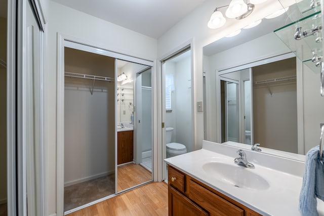 bathroom with vanity, hardwood / wood-style flooring, toilet, and walk in shower