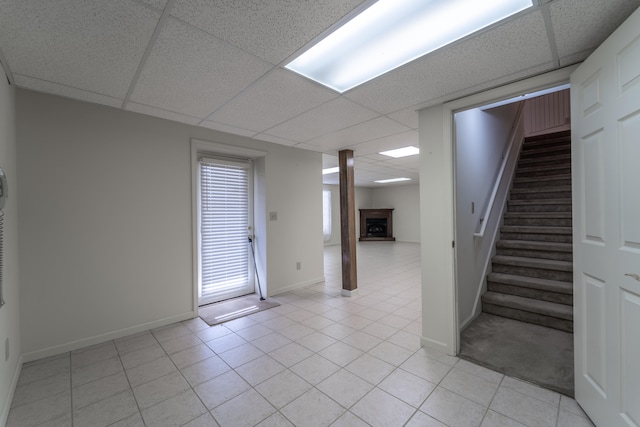 basement featuring a drop ceiling and light tile patterned flooring