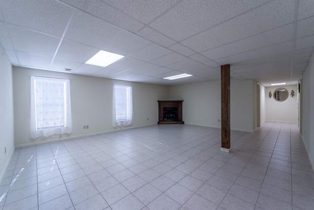 basement with plenty of natural light, a drop ceiling, and light tile patterned floors