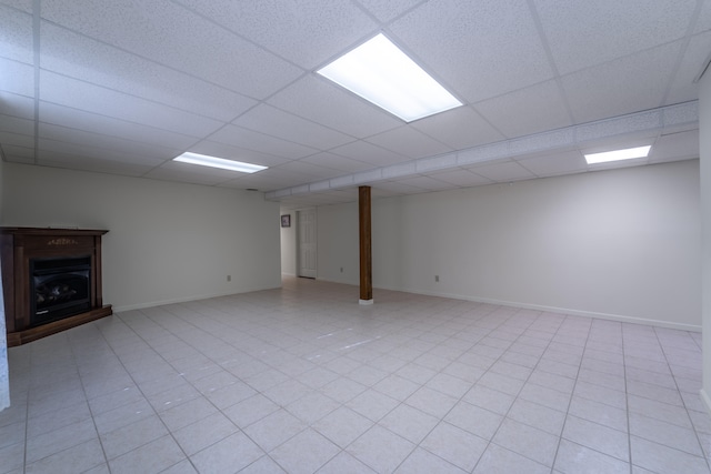 basement with a paneled ceiling and light tile patterned flooring