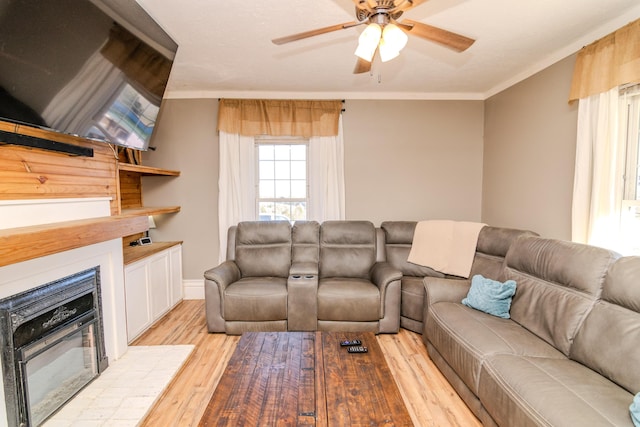 living room with light wood-type flooring, ceiling fan, and ornamental molding